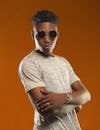 Trendy young man wearing sunglasses posing confidently against an orange background.